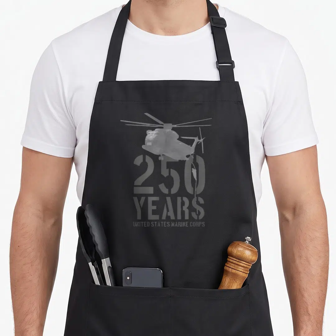 State marine apron - Grey helicopter graphic above 250 YEARS UNITED STATES MARINE CORPS stencil text — shown on a black cotton canvas apron against a white background