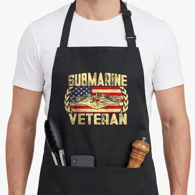 Submarine veteran patriotic apron - Distressed beige SUBMARINE VETERAN text over two submarines and US flag inside — shown on a black cotton canvas apron against a white background
