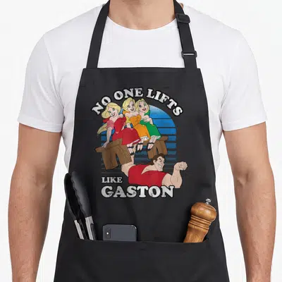 Lift galveston apron - Gaston lifting bench with three women under No One Lifts Like Gaston text — shown on a black cotton canvas apron against a white background