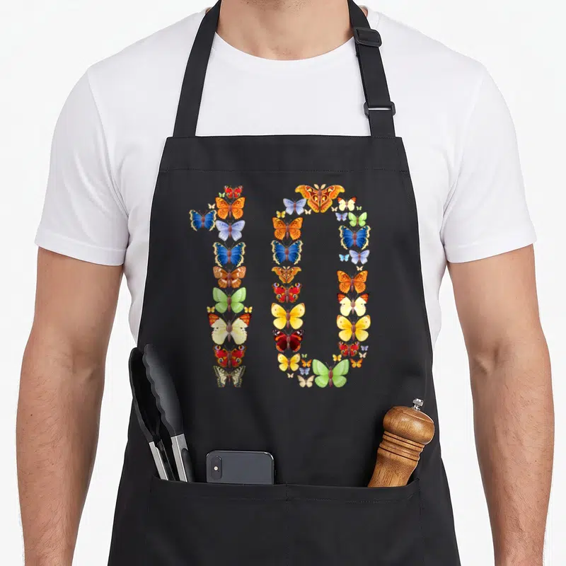 10th birthday butterfly aprons - Realistic blue orange yellow green red butterflies arranged to form the number 10 — shown on a black cotton canvas apron against a white background
