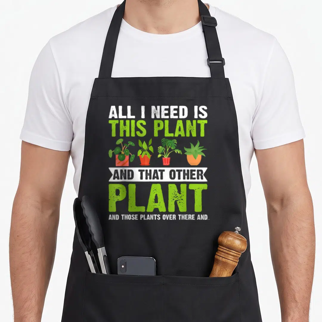 Cute plant gardener apron - Stacked text ALL I NEED IS THIS PLANT with four potted plants in red and orange pots — shown on a black cotton canvas apron against a white background