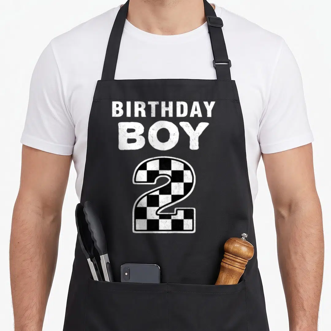 Birthday race 2nd apron - Distressed BIRTHDAY BOY text above black and white checkerboard number 2 — shown on a black cotton canvas apron against a white background