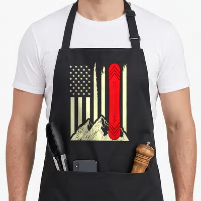Snowboarding american flag apron - Red snowboard standing vertically before cream stars and stripes with mountain peaks — shown on a black cotton canvas apron against a white background