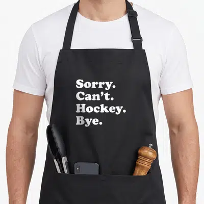 Funny hockey apron or apron - White text reading Sorry Can't Hockey Bye stacked in four lines — shown on a black cotton canvas apron against a white background