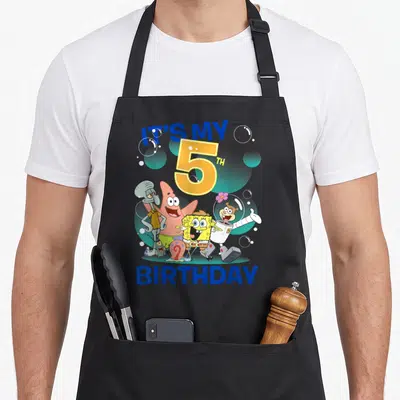 Squarepant 5th birthday apron - IT'S MY 5TH BIRTHDAY text with cartoon characters and bubbles — shown on a black cotton canvas apron against a white background