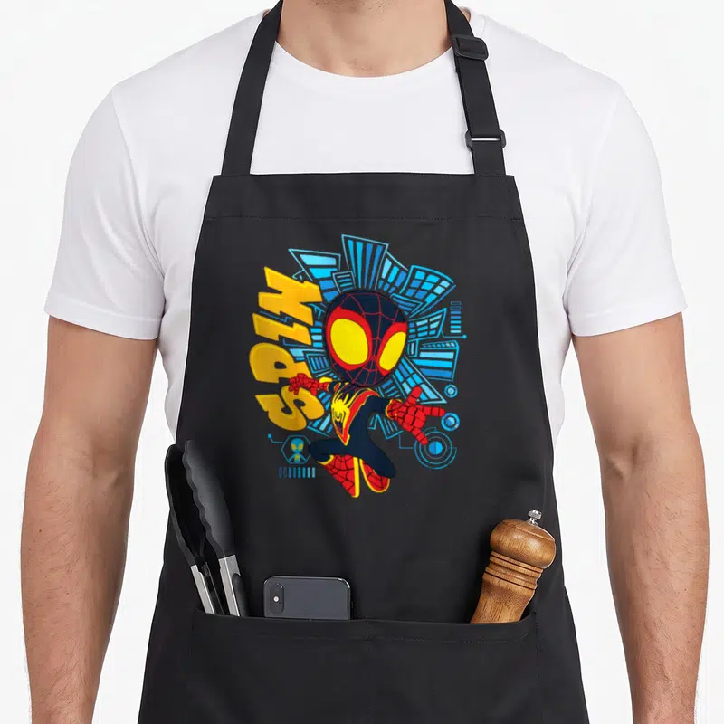 His friends apron - Miles Morales Spider-Man cartoon figure with vertical SPIN text and blue geometric skyline — shown on a black cotton canvas apron against a white background