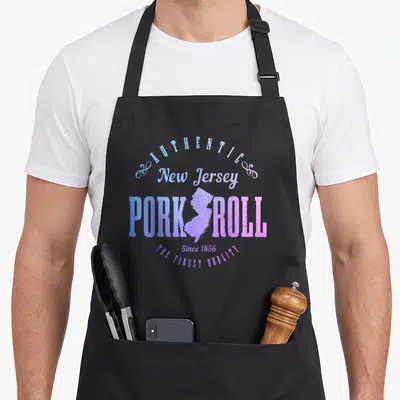 Roll pride apron - New Jersey state map inside PORK ROLL text with AUTHENTIC and THE FINEST QUALITY in blue purple pink — shown on a black cotton canvas apron against a white background