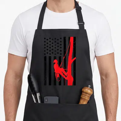 Arborist 4th of july apron - Red arborist silhouette climbing tree integrated into distressed black and grey American — shown on a black cotton canvas apron against a white background