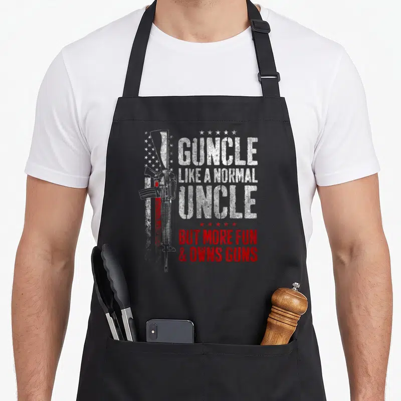 Guncle gun apron - Rifle and stars with Guncle Like Normal Uncle But More Fun Owns Guns text in white and red — shown on a black cotton canvas apron against a white background