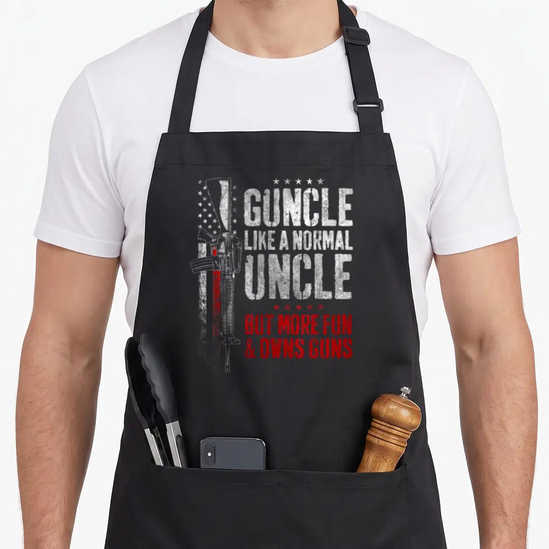 Guncle gun apron - Rifle and stars with Guncle Like Normal Uncle But More Fun Owns Guns text in white and red — shown on a black cotton canvas apron against a white background
