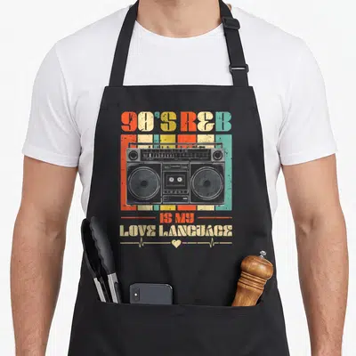 90s music r aprons - Retro boombox over orange, yellow, teal, grey stripes with 90'S R&B text and heartbeat line — shown on a black cotton canvas apron against a white background