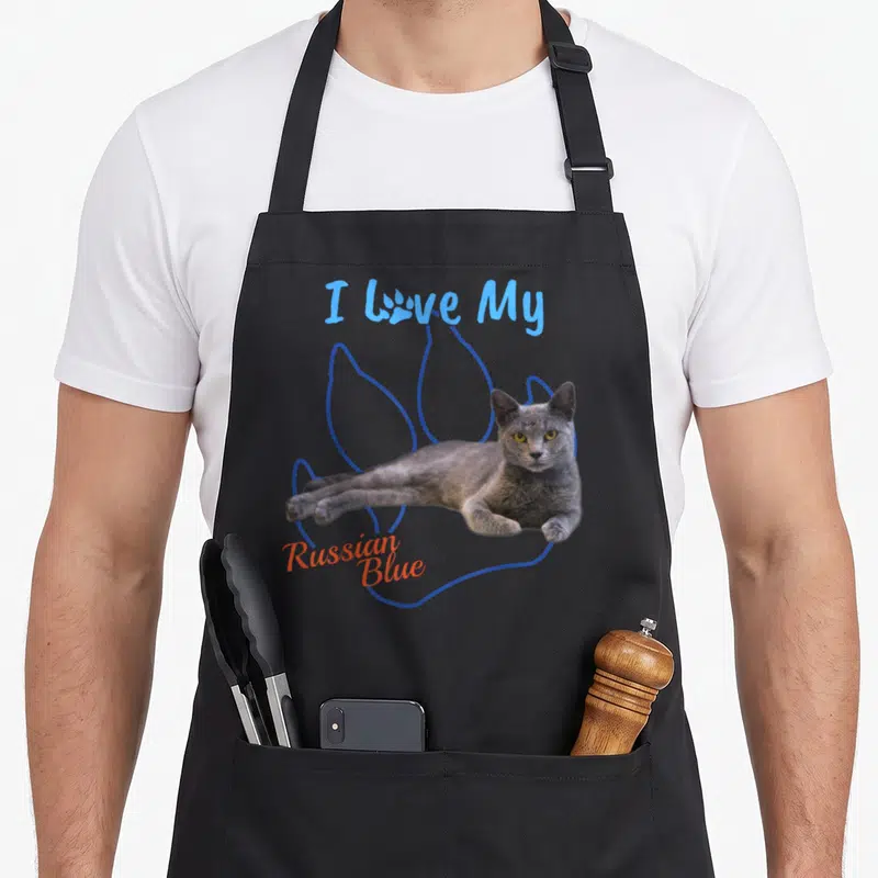 Paw russian aprons - I Love My Russian Blue text with grey cat photo on blue paw print outline — shown on a black cotton canvas apron against a white background