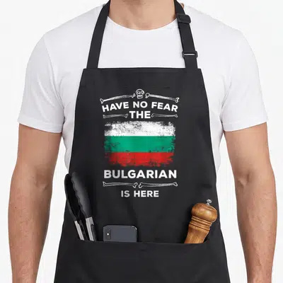 Fear bulgarian apron - Distressed Bulgarian flag with skull crossbones and text HAVE NO FEAR THE BULGARIAN IS HERE — shown on a black cotton canvas apron against a white background
