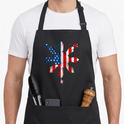 Filipino 4th of july apron - Distressed American flag snowflake with three red and blue stars on black background — shown on a black cotton canvas apron against a white background