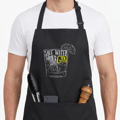 Gin cocktail apron - Save Water Drink Gin text over line art glass with ice and lime slice — shown on a black cotton canvas apron against a white background