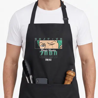 Pirate anime apron - Zoro face in rectangle with Katakana and Pirate Hunter text in green and white — shown on a black cotton canvas apron against a white background