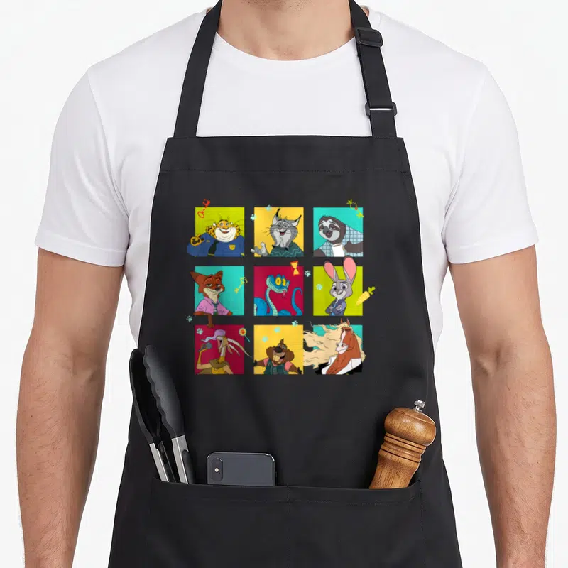 Illustrated grid character aprons - Nine Zootopia characters in a 3x3 grid of yellow, blue, red, green, and orange — shown on a black cotton canvas apron against a white background