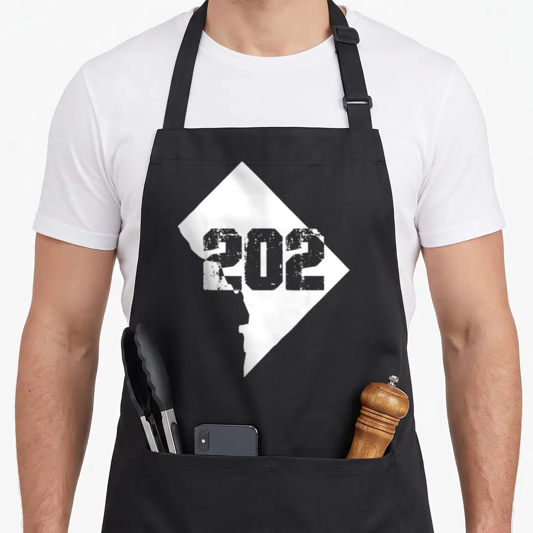 Area washington boy apron - White diamond shape containing the grey number 202 in distressed lettering — shown on a black cotton canvas apron against a white background