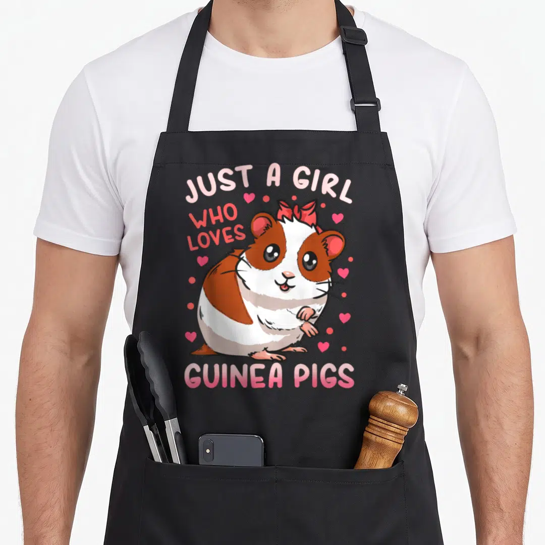 Guinea pig mom apron - Cartoon brown and white guinea pig with pink bow and hearts under arched text — shown on a black cotton canvas apron against a white background