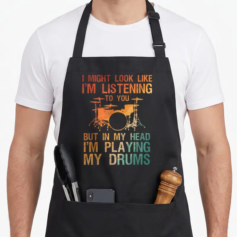 Player drum apron - Distressed orange and teal drum kit with sarcastic text about playing drums in head — shown on a black cotton canvas apron against a white background