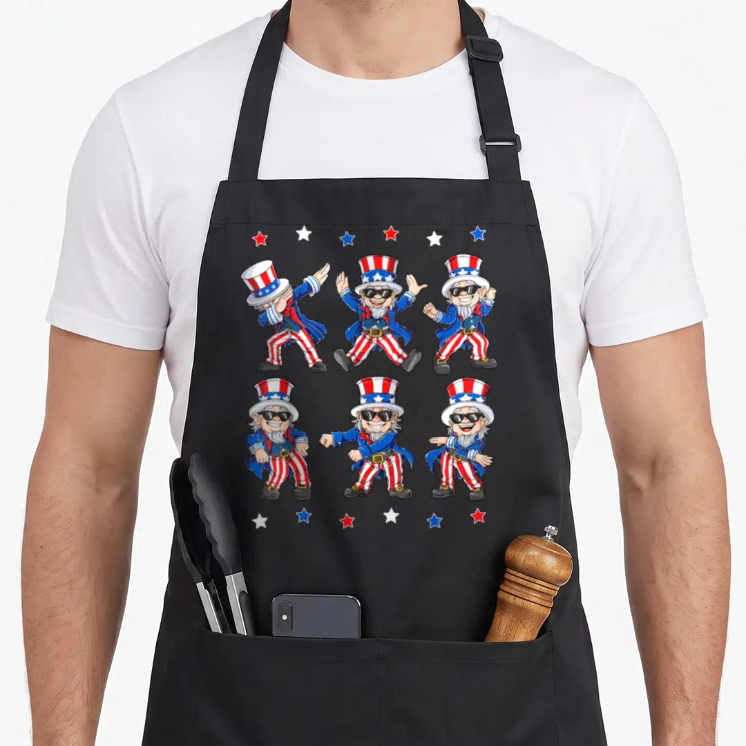 Dancing 4th of july apron - Six Uncle Sam gnomes in red white and blue dance poses framed by stars — shown on a black cotton canvas apron against a white background