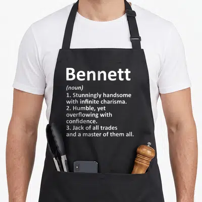 Bennett father day aprons - White text defining Bennett as handsome, humble, and a master of trades on black fabric — shown on a black cotton canvas apron against a white background