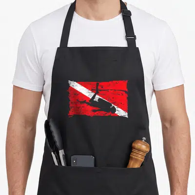 Scuba flag diving apron - Distressed red and white diagonal stripe flag with centered grey diver silhouette — shown on a black cotton canvas apron against a white background