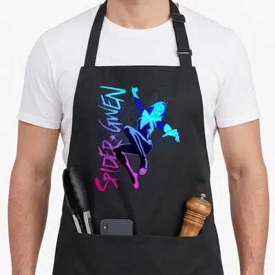 Gwen spider apron - Spider-Gwen cartoon figure with vertical blue purple pink text on web background — shown on a black cotton canvas apron against a white background