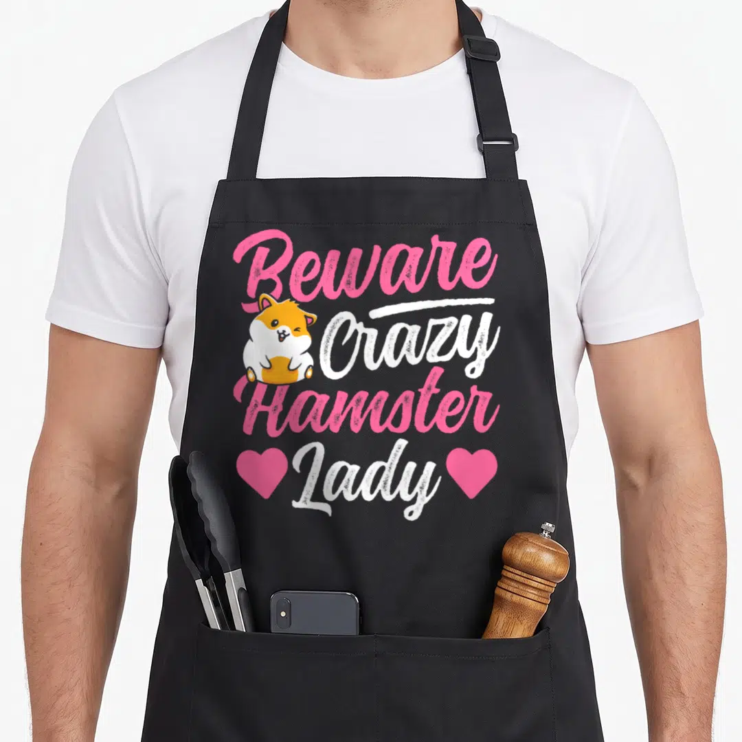 Cute beware crazy hamster lady apron - Winking orange and white hamster with pink hearts and Beware Crazy Hamster Lady — shown on a black cotton canvas apron against a white background