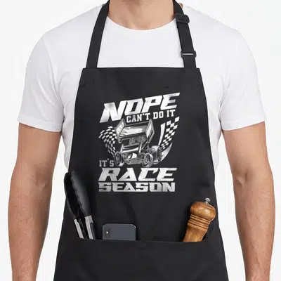 Race sprint track apron - White sprint car with checkered flags and nope can't do it race season text — shown on a black cotton canvas apron against a white background