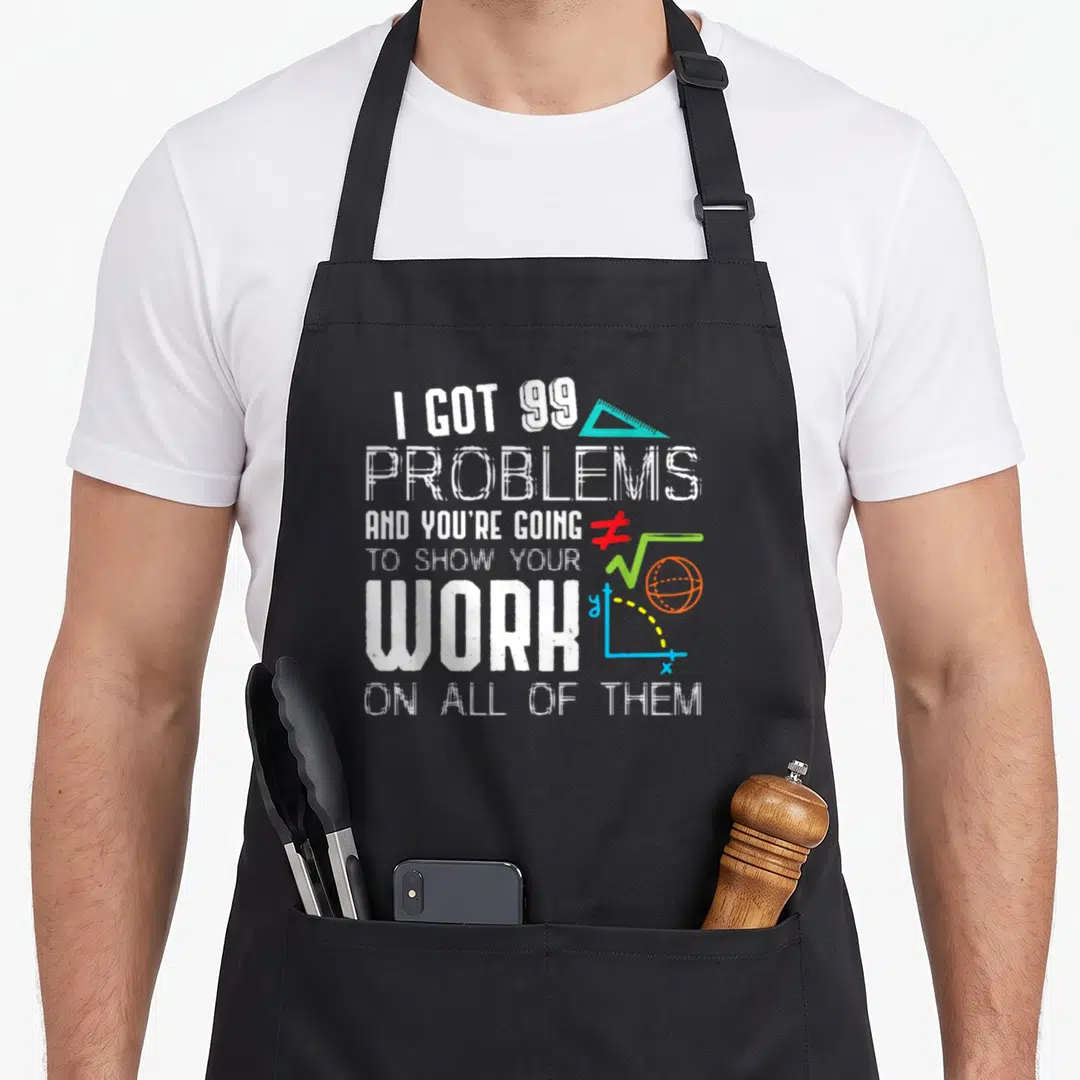 Tutor teacher apron - Stacked white text I GOT 99 PROBLEMS with teal triangle and red inequality symbol — shown on a black cotton canvas apron against a white background
