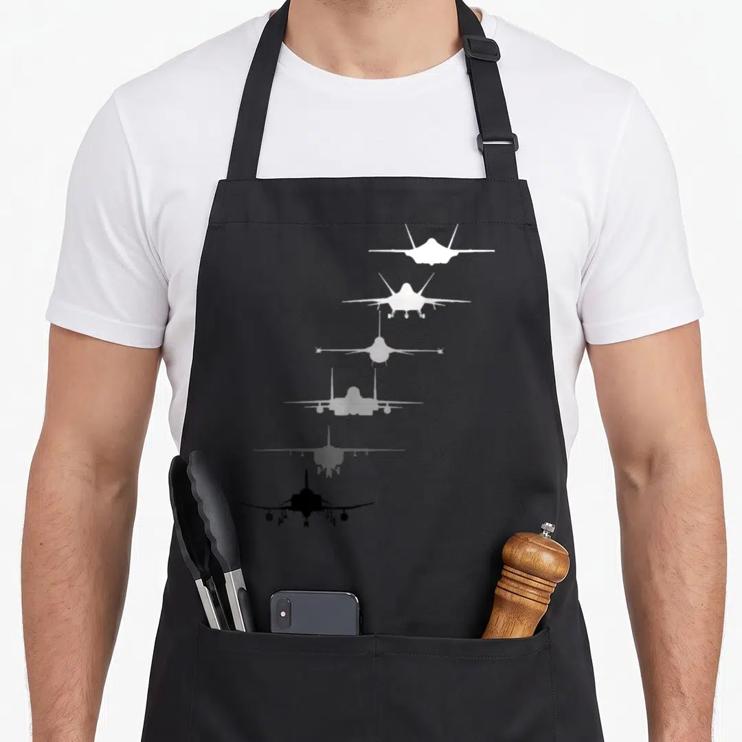 Fighter air force apron - Six jet silhouettes stacked vertically in a white to black gradient — shown on a black cotton canvas apron against a white background