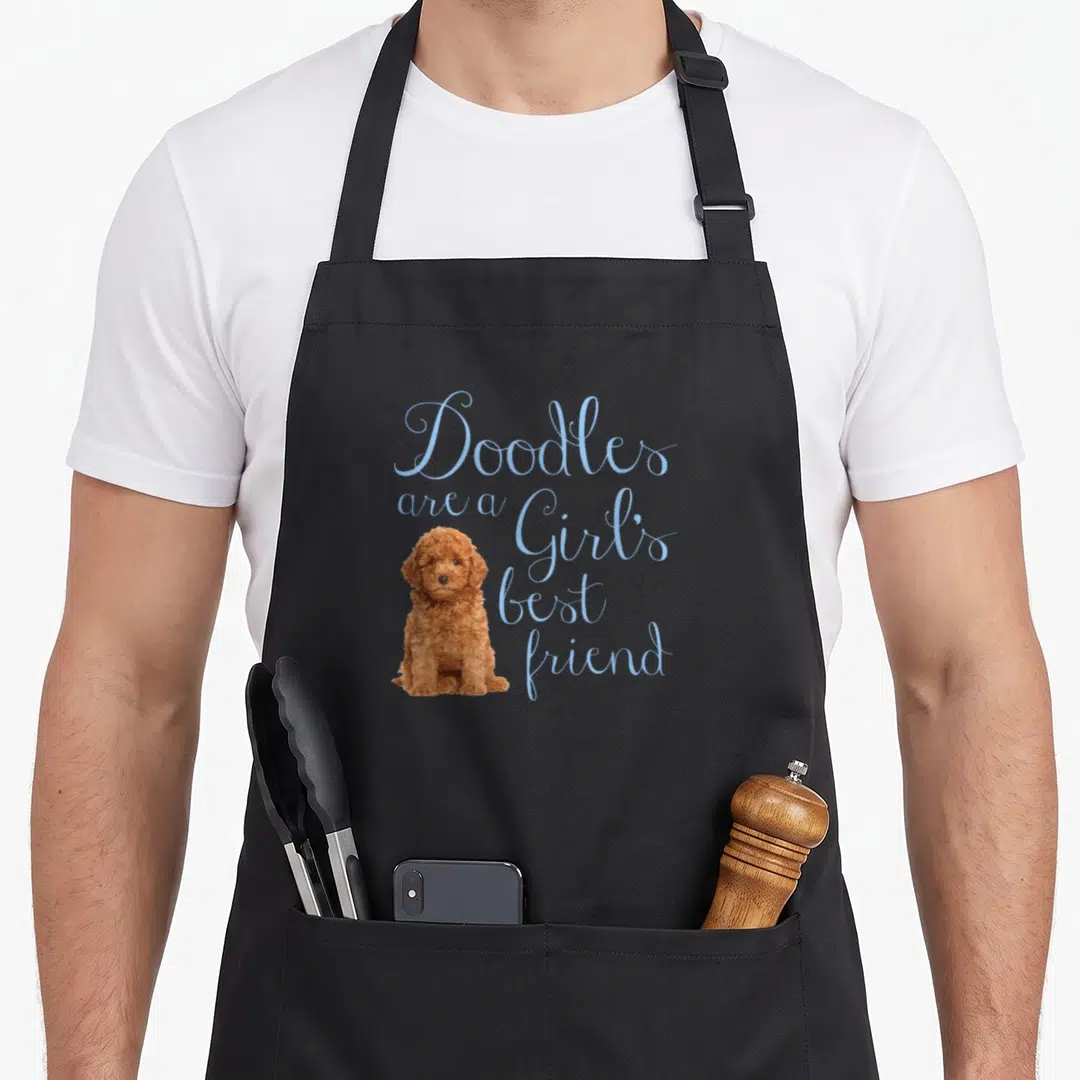 Doodle friend dog apron - Brown doodle sitting next to light blue script text reading Doodles are a Girl's best friend — shown on a black cotton canvas apron against a white background