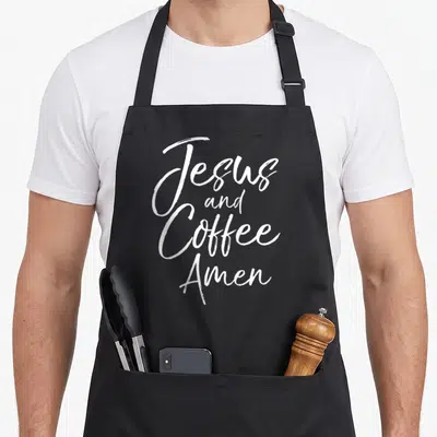 Amen coffee apron - White stacked script text reading Jesus and Coffee Amen — shown on a black cotton canvas apron against a white background