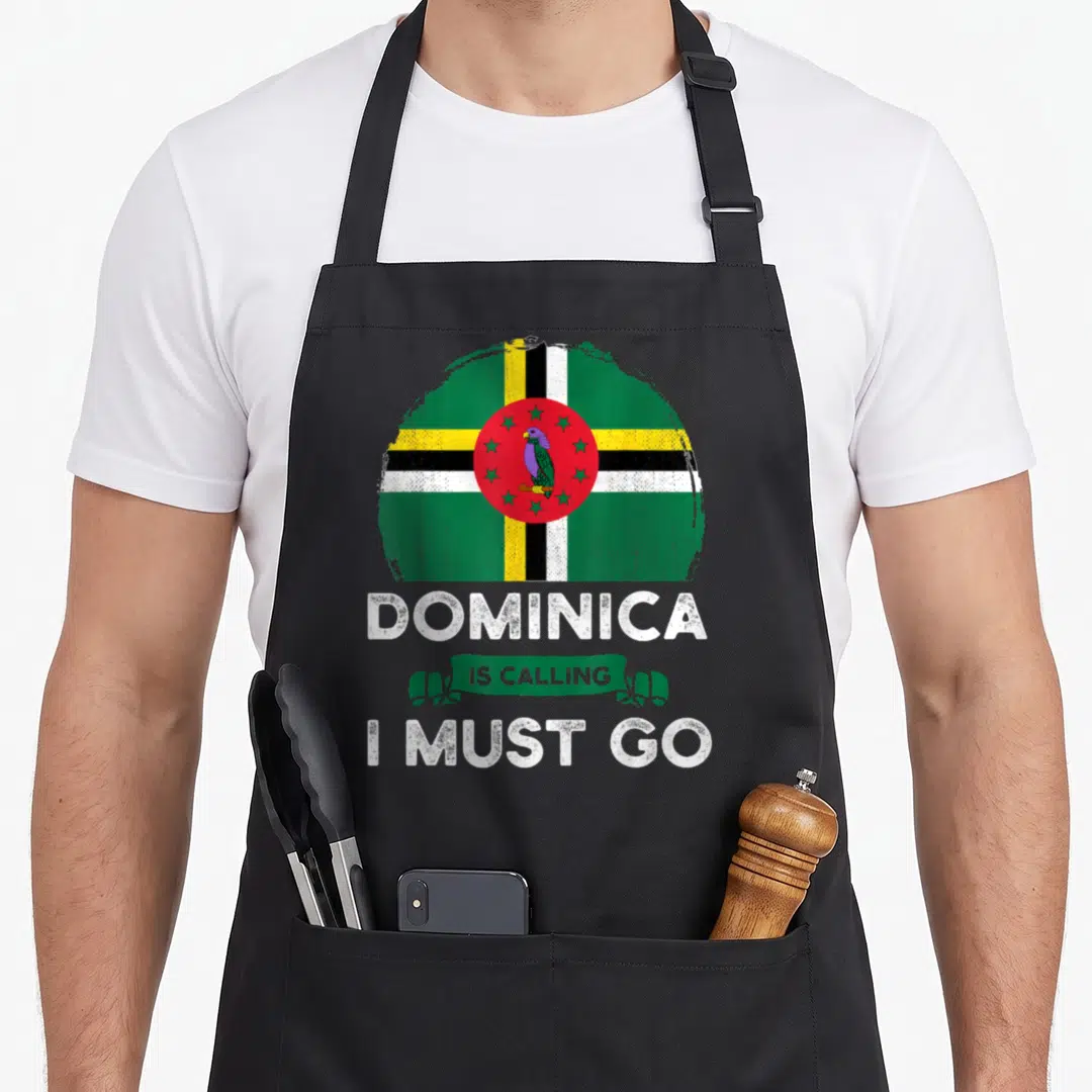 Calling heritage aprons - Distressed circular Dominica flag with green banner reading Is Calling I Must Go — shown on a black cotton canvas apron against a white background