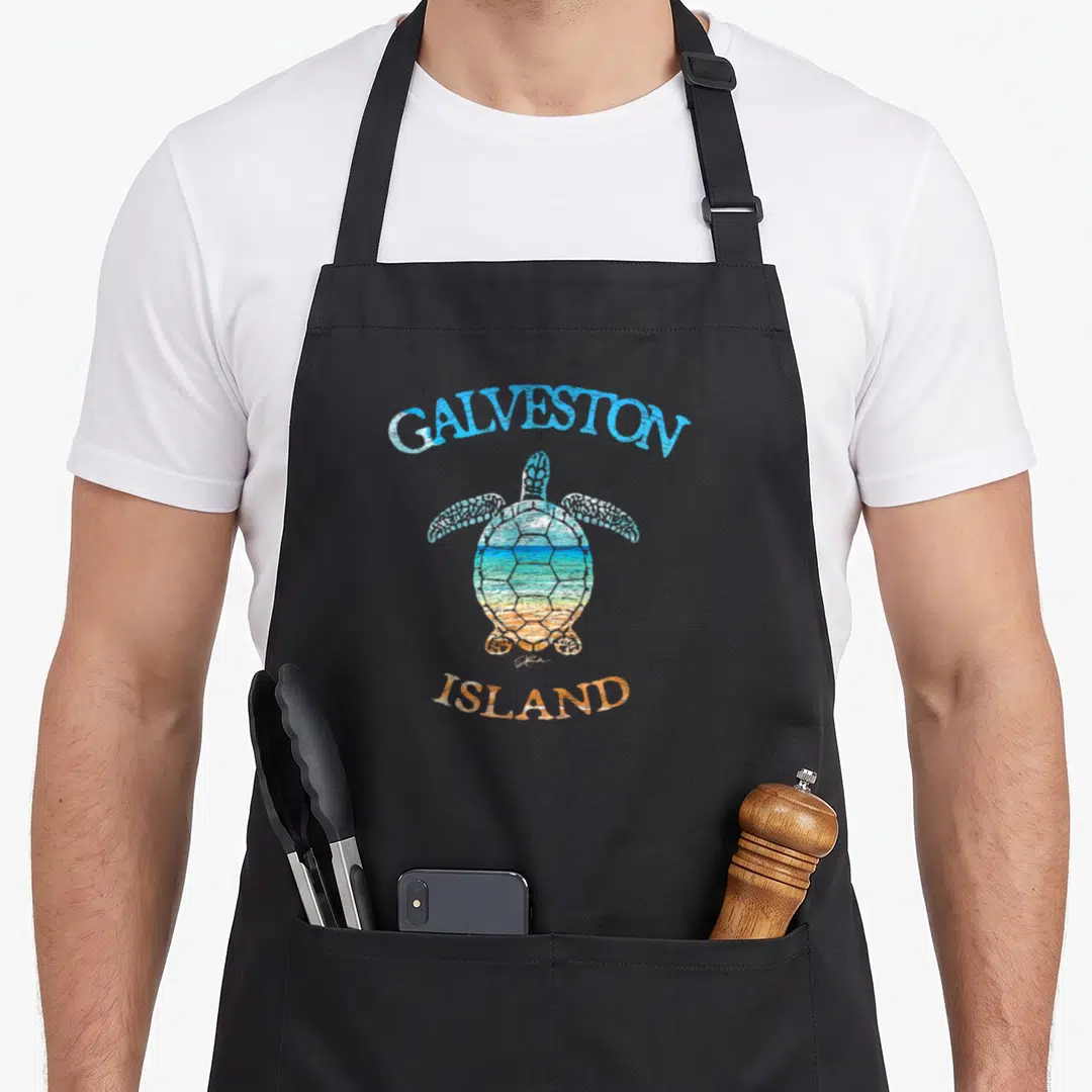Sea galveston island apron - Sea turtle with beach scene in shell, arched GALVESTON ISLAND text in blue and orange — shown on a black cotton canvas apron against a white background