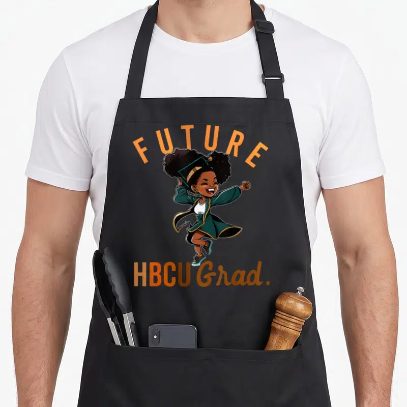 Hbcu future history apron - Cartoon graduate jumping with FUTURE HBCU Grad text — shown on a black cotton canvas apron against a white background