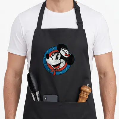 Sailor distressed apron - Minnie Mouse head in sailor hat inside blue porthole with red neckerchief and distressed — shown on a black cotton canvas apron against a white background