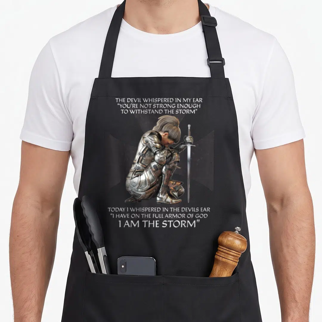 Distressed christian apron - Kneeling knight in silver armor before black cross with full armor of god quote — shown on a black cotton canvas apron against a white background