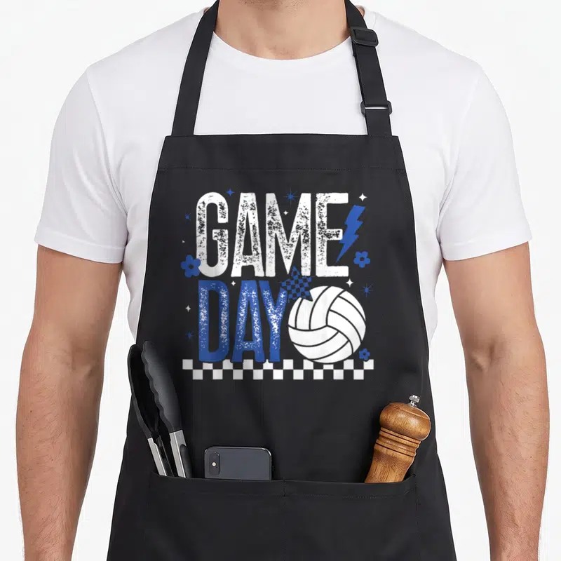 Volleyball checkered apron - GAME DAY text with volleyball, lightning bolt, flowers, stars, and checkered border — shown on a black cotton canvas apron against a white background