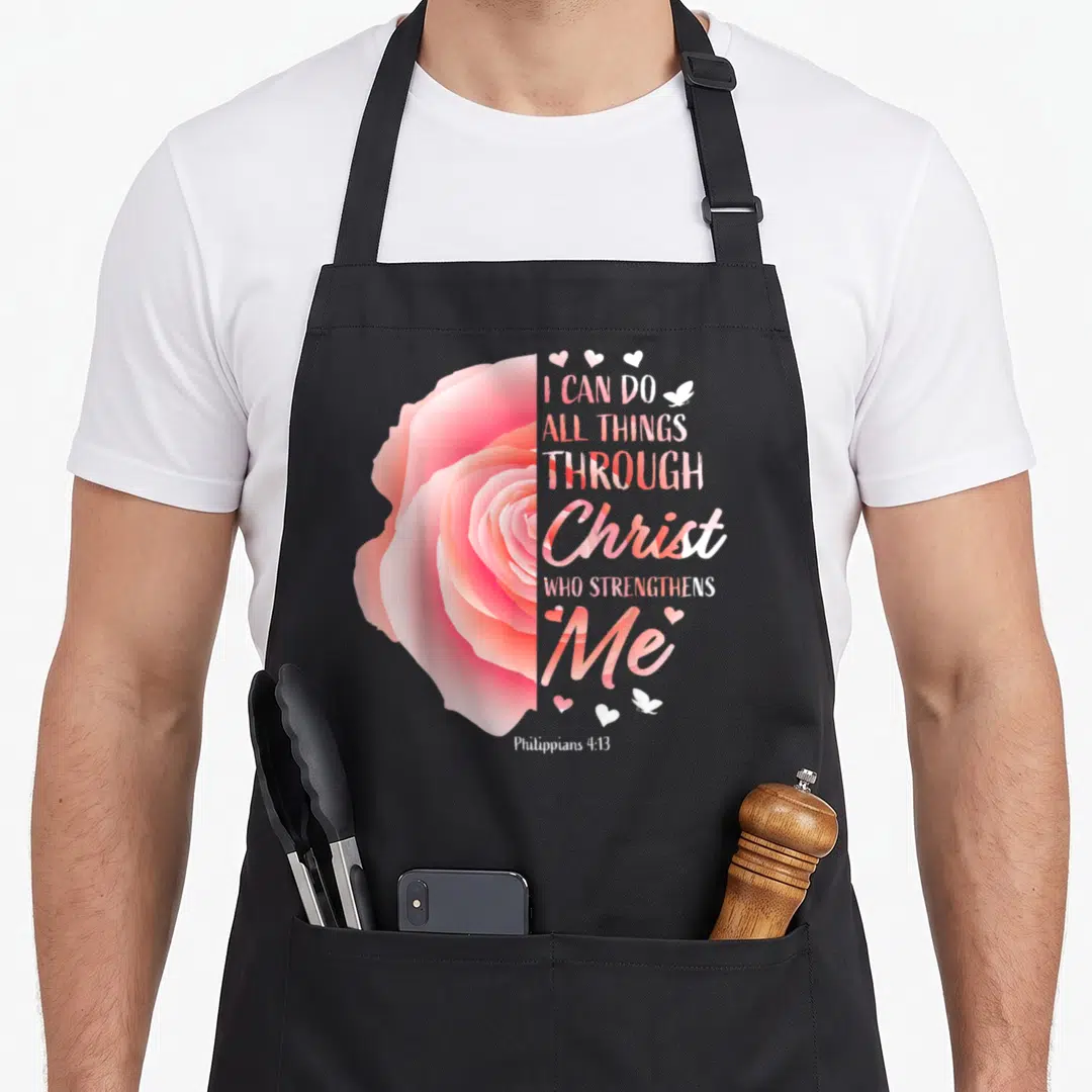 Philippian christian bible verse apron - Realistic pink and orange rose next to stacked scripture text with hearts — shown on a black cotton canvas apron against a white background