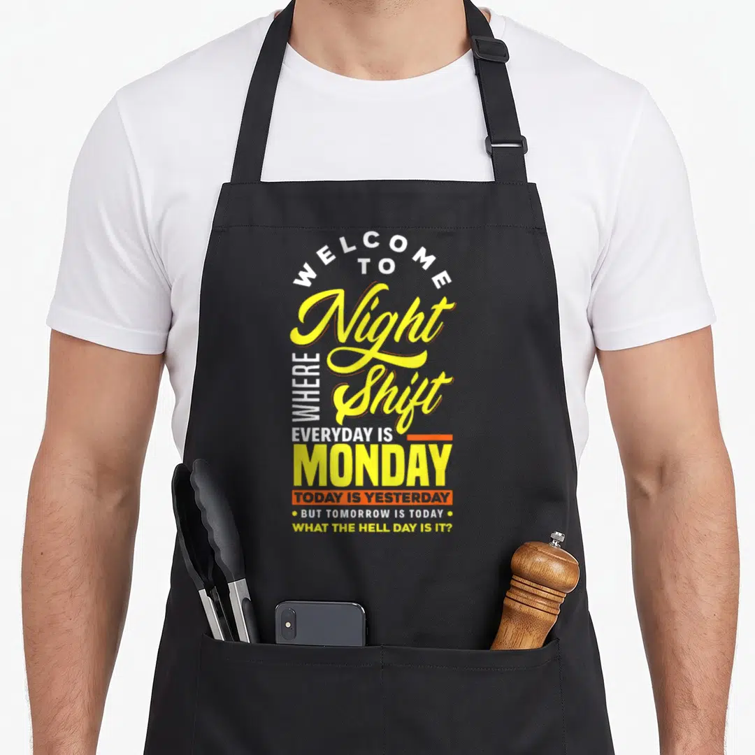 Night pun apron - Yellow and white typography reading Welcome to Night Shift Monday sarcasm — shown on a black cotton canvas apron against a white background