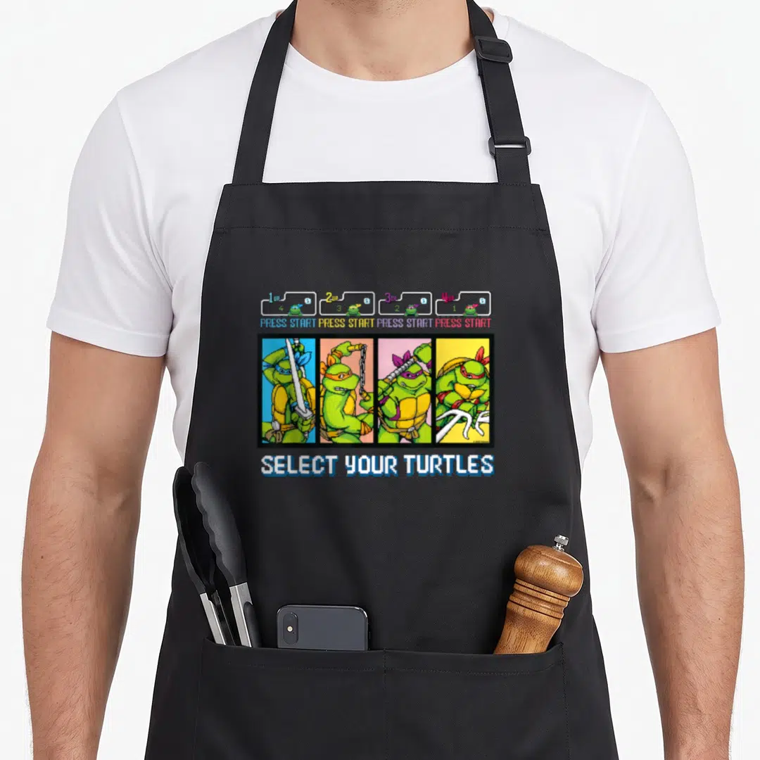 Select teenage mutant ninja apron - Pixel art Teenage Mutant Ninja Turtles select screen with 1up 2up 3up 4up PRESS — shown on a black cotton canvas apron against a white background