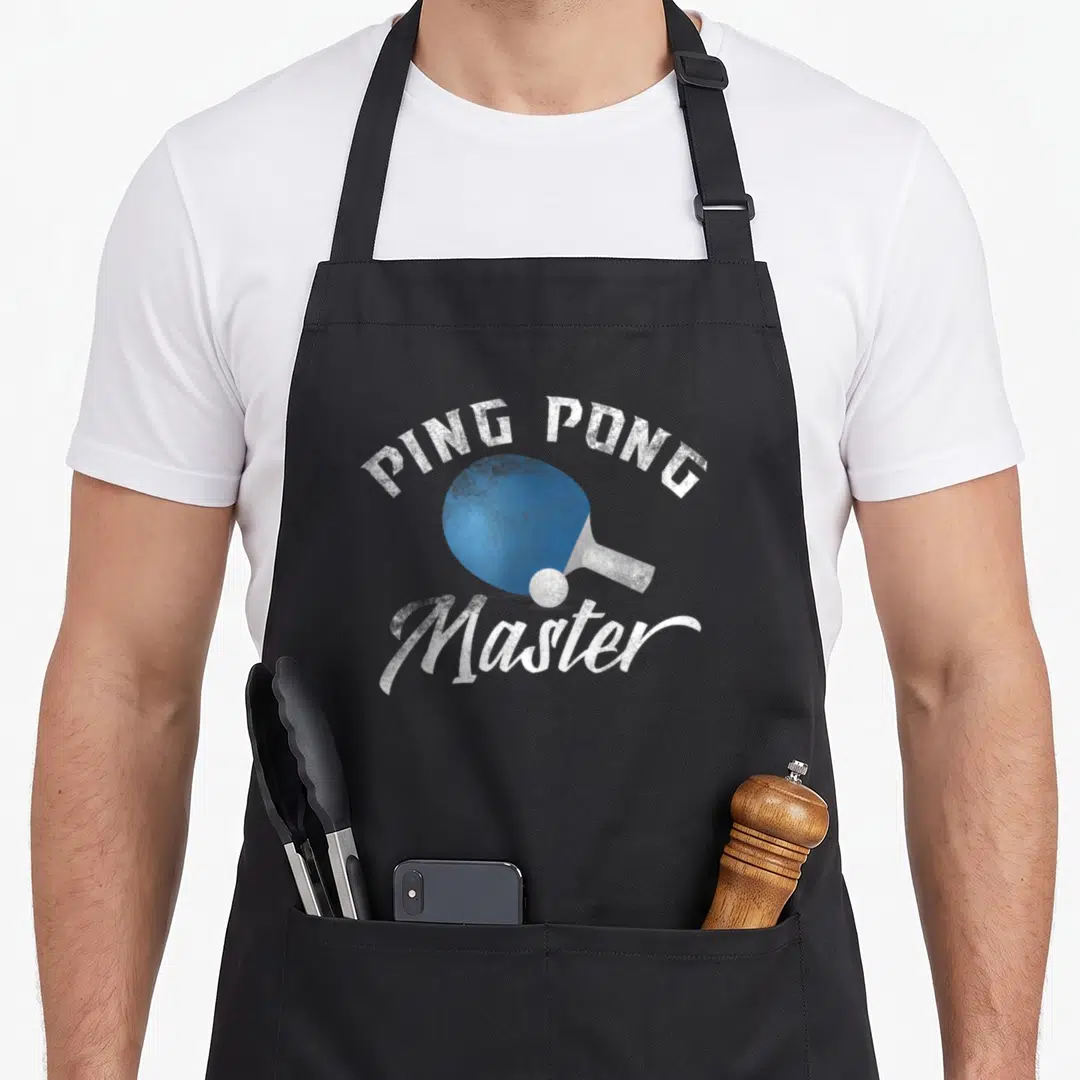 Blue table apron - Blue ping pong paddle and white ball with distressed PING PONG Master text — shown on a black cotton canvas apron against a white background