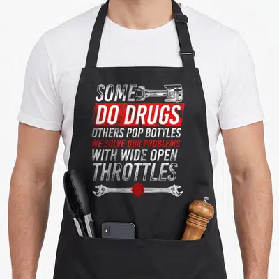 Wide open apron - Stacked white and red text with piston and wrench containing a central skull in distressed style — shown on a black cotton canvas apron against a white background
