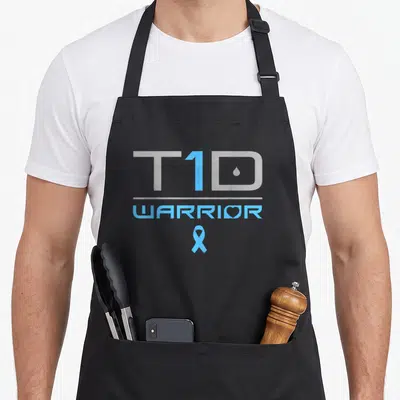Cute diabetic diabetes awareness apron - Cyan and grey T1D WARRIOR text with a heart in the O and a blue awareness — shown on a black cotton canvas apron against a white background