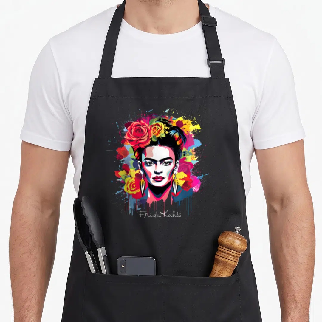 Mexican frida kahlo apron - Realistic Frida Kahlo portrait with red yellow blue pink roses and paint splashes — shown on a black cotton canvas apron against a white background