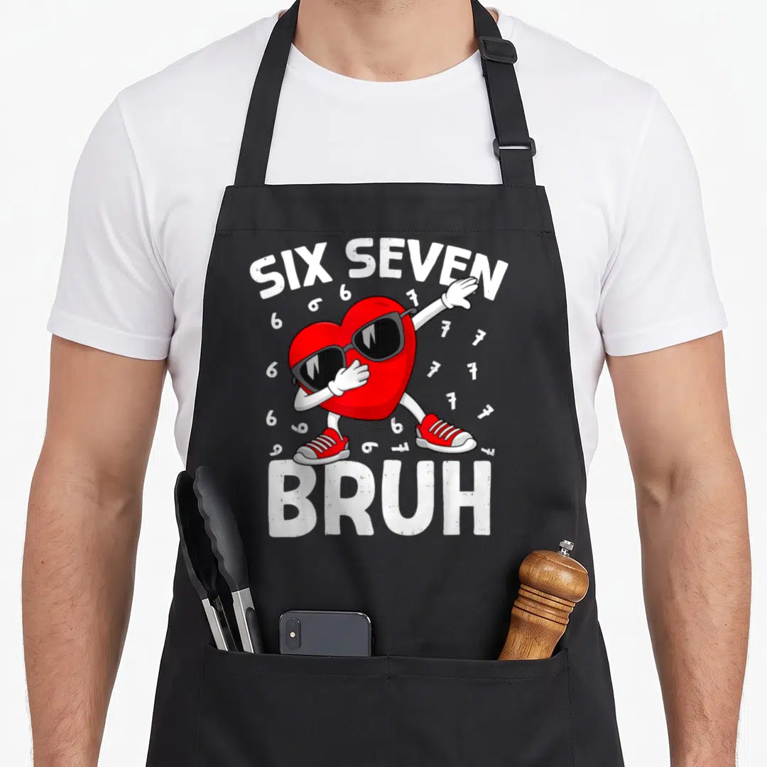 Six valentine's day apron - Dabbing red heart character with sunglasses and sneakers surrounded by SIX SEVEN and BRUH — shown on a black cotton canvas apron against a white background