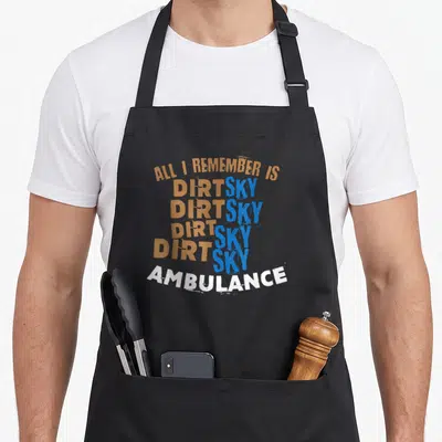 Motocross sky apron - Stacked orange blue and white text reading ALL I REMEMBER IS DIRT SKY AMBULANCE — shown on a black cotton canvas apron against a white background