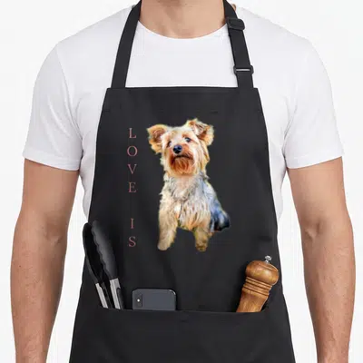 Yorkshire terrier yorkie apron - Photo of a brown and tan dog beside vertical pink text reading LOVE IS — shown on a black cotton canvas apron against a white background
